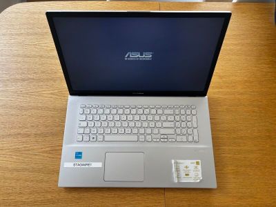 L'ordinateur portable Asus est posé sur une table en bois, avec une carte SIM insérée dedans.