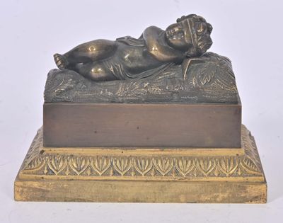 une statue en bronze représentant un bébé allongé sur un lit