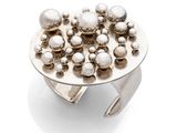 silver plated ring with silver balls on it on a white surface