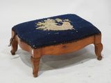 un petit repose-pieds sur lequel est posé un coussin bleu