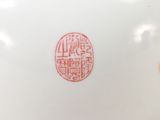 a white vase with a red design on it