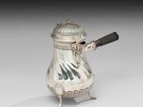 une cafetière ancienne en argent, munie d'une anse et posée sur un socle