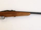 un fusil posé sur une surface blanche, avec une crosse noire