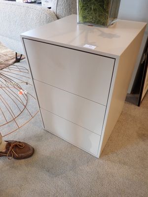 une commode blanche sur laquelle est posée une plante