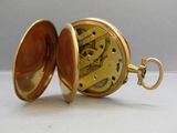 une montre de poche en or posée ouverte sur la table