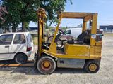 une petite voiture blanche et un chariot élévateur jaune