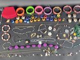de nombreux bracelets et colliers de différentes couleurs disposés sur une table