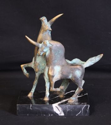 a bronze statue of a man riding a bull on a marble base