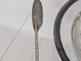 a silver plate with a feather on it next to a glass bowl