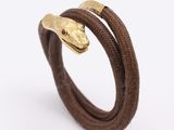 un bracelet en forme de serpent, orné d'une tête de serpent en or, monté sur un cordon en cuir marron