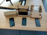 Plusieurs téléphones portables sont posés sur une table, recouverts de boîtes.