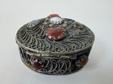 a silver box with red and white stones on it