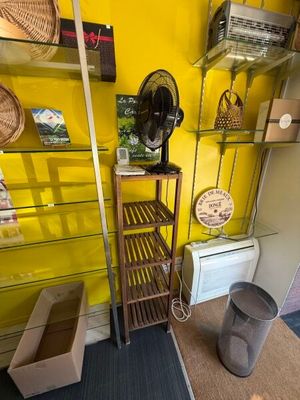un mur jaune avec des étagères et un ventilateur dans un coin