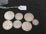 several silver coins sitting on top of a black surface next to a tag