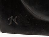 black sculpture of a bird on a black base on a white surface
