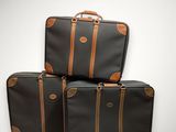 trois bagages empilés les uns sur les autres sur une surface blanche