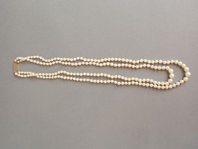 un gros plan sur un collier de perles blanches muni d'un fermoir doré