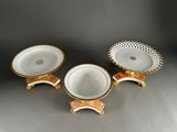 three white and gold dishes with gold trims on stands