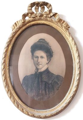 une vieille photo d'une femme en robe noire, dans un cadre doré