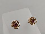 a pair of gold earrings with pink stones on a white surface