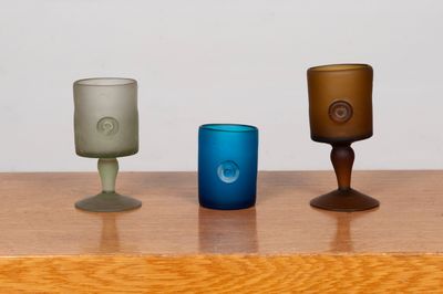 three different colored glasses sitting on a wooden table