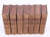 several old books stacked on top of each other on a white surface