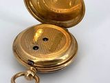 a gold pocket watch sitting on a white surface