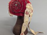 a red hat on a wooden stand with a ribbon around it