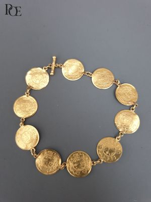 un bracelet en or orné d'un motif représentant une pièce de monnaie