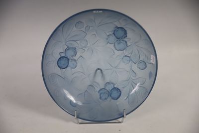 une assiette bleue décorée de fleurs bleues, posée sur un socle