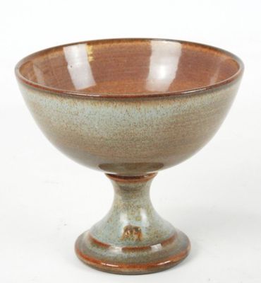a brown and green bowl sitting on a white surface