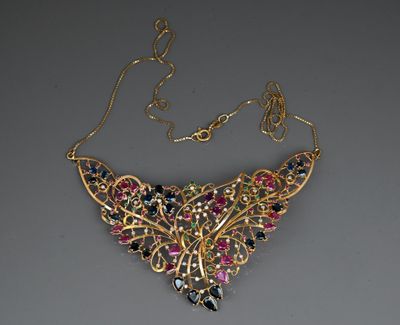 a close up of a gold necklace with multi colored stones on it