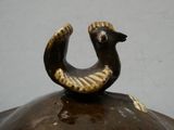 a brown vase with a bird on top of it