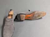grey sued loafer shoes with orange soles on a grey surface