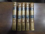 Quatre livres sont empilés en rangée sur une table en bois.