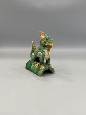 une figurine verte et dorée représentant un chat assis sur un rocher