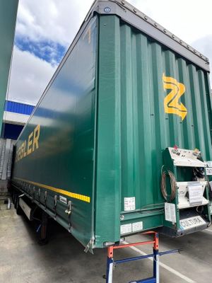 a large green container truck parked in a parking lot
