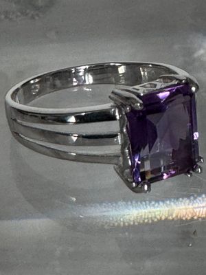 une bague ornée d'une pierre violette, posée sur une table