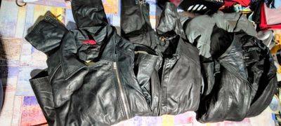several pairs of black leather gloves sitting on top of a bed