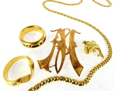 a gold necklace, ring, and other jewelry laid out on a white surface