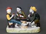 three figurines of men sitting at a table playing cards