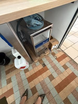 une personne debout sous un plan de travail de cuisine, à côté d'un micro-ondes