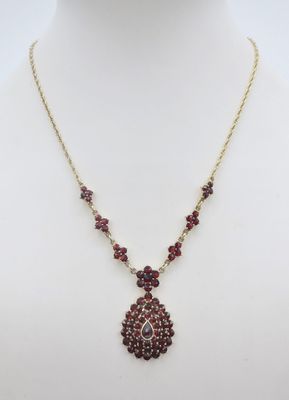 un collier avec une pierre rouge et une chaîne en or sur un mannequin