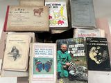 beaucoup de livres posés sur une table, avec un homme assis à côté