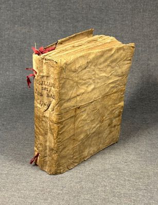 an old book with a red ribbon is sitting on a gray surface