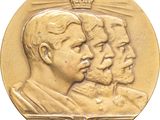 an image of a gold medal with three men and a crown on it