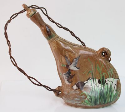 un vase marron orné d'oiseaux peints, posé sur une table