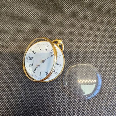 une petite horloge posée à côté d'une boule de verre sur une table