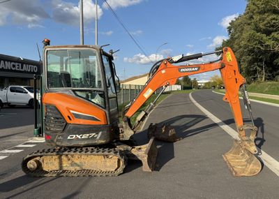 an orange excavator that is parked on the side of the road