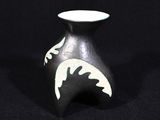 un petit vase noir orné d'un motif blanc